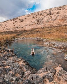 there is a man swimming in the water at the top of a hill on a sunny day