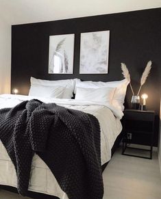 a black and white bedroom with two framed pictures on the wall above the bed, along with candles