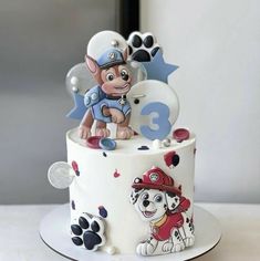 a birthday cake decorated with paw patrol characters and dog figures on it's side