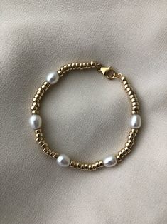 A modern gold and pearl bracelet that looks great on its own or stacked.  A statement piece with a classic style. Features lustrous pearls + high quality 14kt gold filled beads and closures. Measures approx. 7" Comes packaged in a cotton pouch and resealable bag.  ---------------------------------------------------------------------------- >> Check out the entire shop here: https://www.etsy.com/ca/shop/standingoaccessories >> Follow is on Instagram:  http://instagram.com/standing_o_accessories P Modern Gold Pearl Bracelets, Modern Gold Pearl Bracelet, Adjustable Gold Pearl Bracelet In Modern Style, Gold Pearl Bracelet With Spacer Beads For Everyday, Gold Minimalist Pearl Bracelet With Gold Beads, Modern Gold Pearl Bracelet As Gift, Modern Pearl Bracelet With Pearl Charm For Gift, Modern Pearl Bracelet With Pearl Charm As Gift, Modern Pearl Bracelet With Charm As A Gift