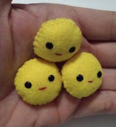 three small yellow balls with black eyes are in someone's hand