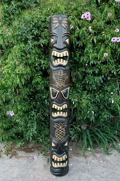 a totem pole sitting in front of some bushes