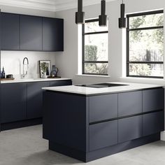 a modern kitchen with black cabinets and white counter tops, along with an island in the middle