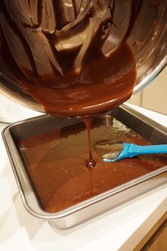 chocolate being poured into a pan with a blue spatula