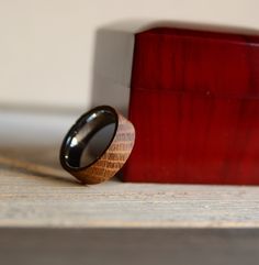 a wooden ring sitting on top of a table next to a red box and white wall