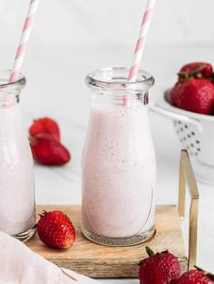 two mason jars filled with strawberry milk next to strawberries