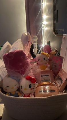 a basket full of hello kitty toys in front of a mirror with lights on it