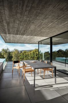 a table and chairs in front of a glass wall with an open window on the other side