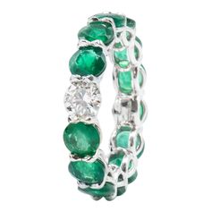 This beautiful Ring features 13 Green Emeralds with 1 Round Brilliant Diamond center totaling 6.46 Carats. 13 Emeralds weigh 5.95 Carats. 1 Diamond weighs 0.51 Carats. Set in Platinum. Finger Size 6 Luxury Gia Certified Round Eternity Band, Green Diamond Round Eternity Band, Luxury Round Gemstone Eternity Band, Formal Round Emerald Ring With Single Cut Diamonds, Elegant Green Round Eternity Band, Green Eternity Band With Vvs Clarity In Round Shape, Emerald Eternity Band For Anniversary, Green Round Cut Eternity Band For Formal Occasions, Round Diamond Cut Platinum Emerald Ring