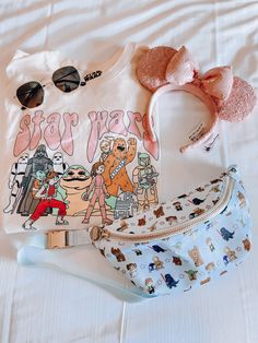 a white shirt with cartoon characters on it and a bow headband next to the bag