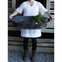 a woman is holding a large bowl with vegetables in it