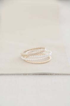 This listing features one sterling silver or 14K gold filled ring. Choose to wear one or stack several! The beaded band is available in both sterling silver and 14K gold filled and has a width of approximately 1.5mm. The twist ring is available in both sterling silver and 14K gold filled and has a width of approximately 1.1mm. The flat bead ring is available in both sterling silver and 14K gold filled and has a width of approximately 2mm. Stack these accent rings with our beautiful handcrafted b Minimalist Hand Wrapped Round Bead Jewelry, Minimalist Hand-wrapped Round Beads Jewelry, Minimalist Stackable Beaded Bracelets, Minimalist Tiny Beads Jewelry For Wedding, Minimalist Tiny Beads Wedding Jewelry, Elegant Beaded Promise Ring, Beaded Toe Rings For Wedding, Delicate White Stackable Rings For Everyday, Minimalist Hand Wrapped Promise Ring