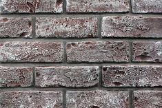 an old brick wall with some snow on it's edges and the top part missing