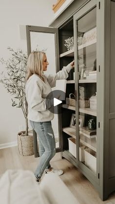 a woman standing in front of an open cabinet