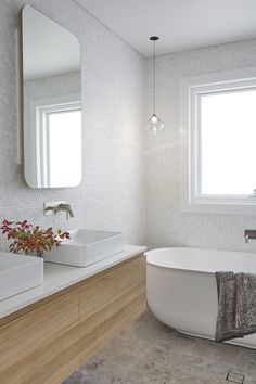 a bathroom with two sinks and a bathtub next to a large mirror on the wall