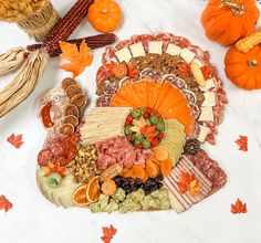 a turkey shaped platter filled with meats, cheese and vegetables next to pumpkins