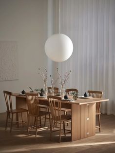 a dining room table with chairs and vases on it