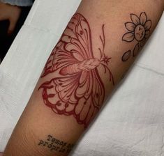 a tattoo on the arm of a person with a butterfly and flower in red ink