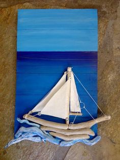 a sailboat is sitting on top of some driftwood in the blue water and sand