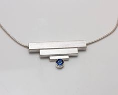 Perfect for the woman who loves minimalist jewelry, this arty necklace features a square tubing arrangement reminiscent of Art Deco design. Modern and sophisticated. The pendant features a bezel set 5mm London Blue topaz.  18"  mm sterling snake chain. Size: Pendant is 1 1/2" wide Tube Art, Deco Bar, Art Deco Bar, Metal Clay Jewelry, Modernist Jewelry, Blue Topaz Pendant, Topaz Pendant, Silver Jewelry Design, Art Deco Necklace