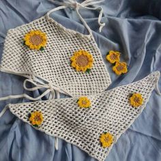 two crocheted sunflowers are sitting on a blue sheet with white drawstring