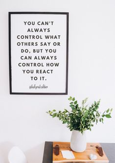 a white vase sitting on top of a wooden table next to a framed quote above it