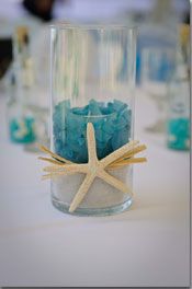 a starfish sits in a glass vase filled with sand