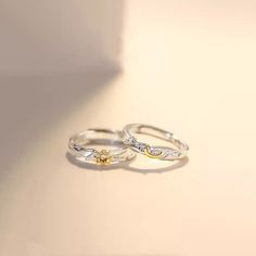 two silver rings with yellow and white diamonds on them, sitting next to each other