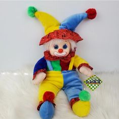 a stuffed clown sitting on top of a white rug