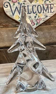 a glass christmas tree sitting on top of a wooden table