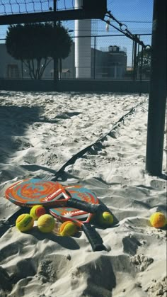 tennis balls and rackets are in the sand