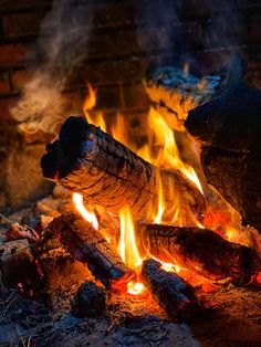 a fire burning in a fireplace with lots of wood