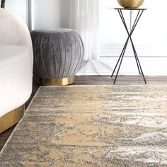 an area rug in a living room next to a chair and table with a vase on it