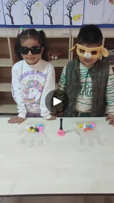 two children sitting at a table with their hands on the table and one child wearing blindfolds