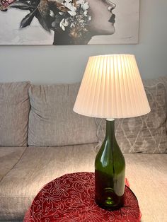 a green bottle sitting on top of a red table next to a white lampshade