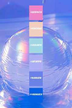 a glass bowl filled with water and different colored labels on the bottom, along with a straw sticking out of it