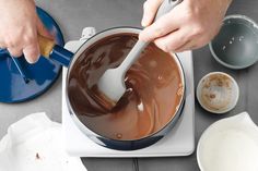 a person stirring chocolate in a pot with a spatula