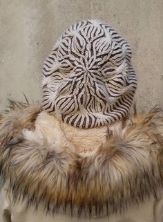 a white and brown hat on top of a fur coat next to a stone wall