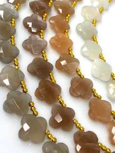 several different colored beads are hanging from a gold plated chain on a white surface