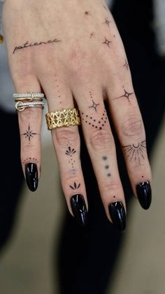 a woman's hand with tattoos on it and two rings in the middle of her fingers