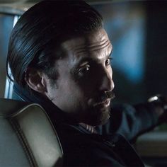 a man sitting in the back seat of a car with his arm out and looking off into the distance