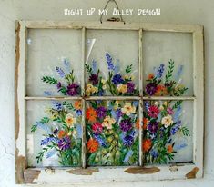 an old window with flowers painted on the glass and hanging from it's side