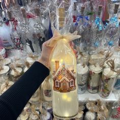 a hand holding a bottle with a house on it in front of many other bottles