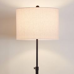 a lamp that is on top of a table with a white shade over the base