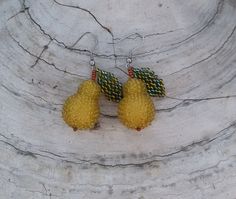 two yellow pomegranates are hanging from earrings