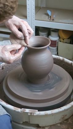 a person is making a vase on a potter's wheel with his hands in it