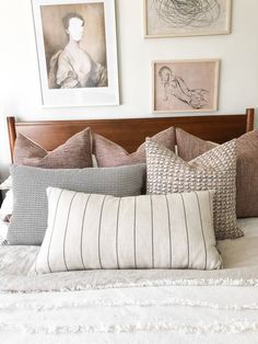 a bed topped with lots of pillows next to pictures on the wall above it's headboard