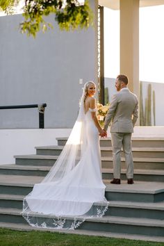 a bride and groom standing on some steps