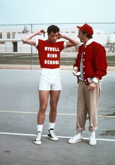 two men standing next to each other on top of a tennis court with their hands behind their heads