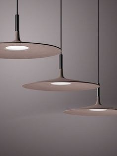 three lights hanging from the ceiling in a room with gray walls and floor to ceiling lighting